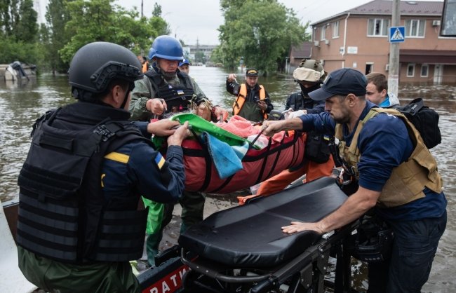 KHERSON, UKRAINE - Jun. 12, 2023: Lifeguards and volunteers seen evacuating helpless old people from flooded areas on stretchers
