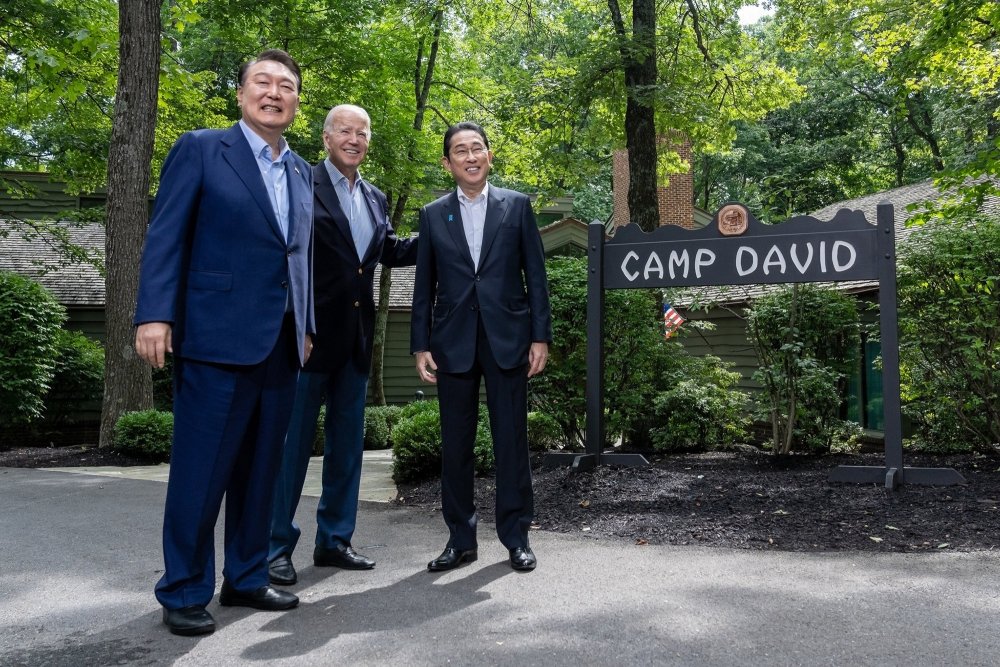 Presidents Yoon and Biden stand with Prime Minister Kishida in front of the sign for Camp David.