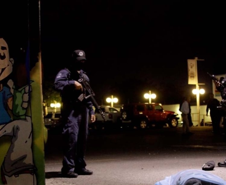 Two policemen stand next to a gunshot victim at night