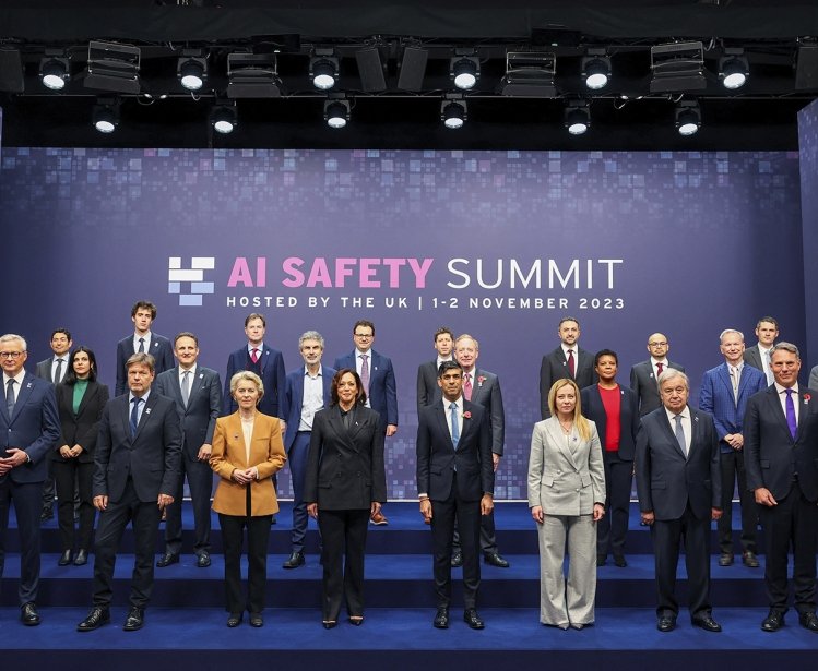A group of world leaders positioned in front of a AI Safety Summit sign in November 2023.