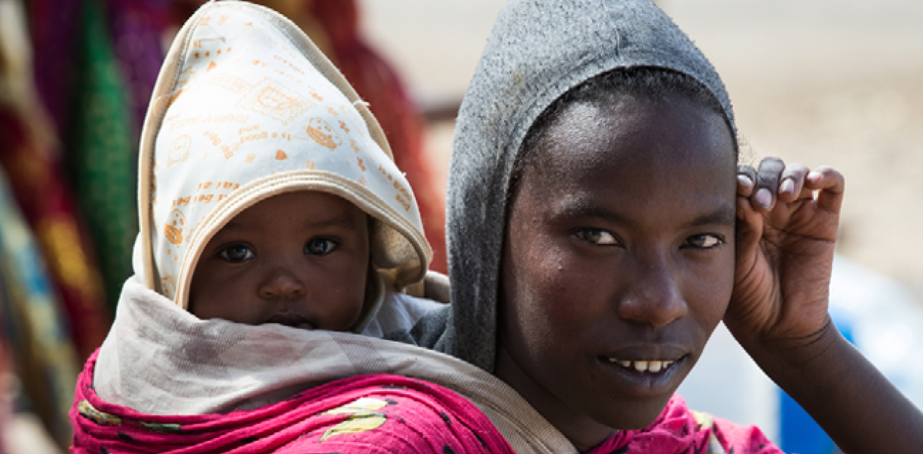 Ethiopian young woman with baby on the back on Addis Ababa Street by Andrzej Kubik/Shutterstock