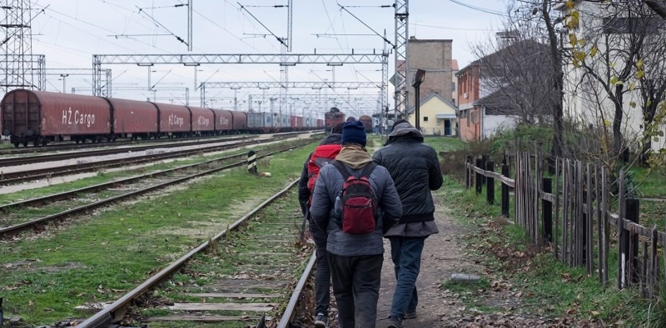 Migrants walking along train tracks in Serbia. Source: Shutterstock.