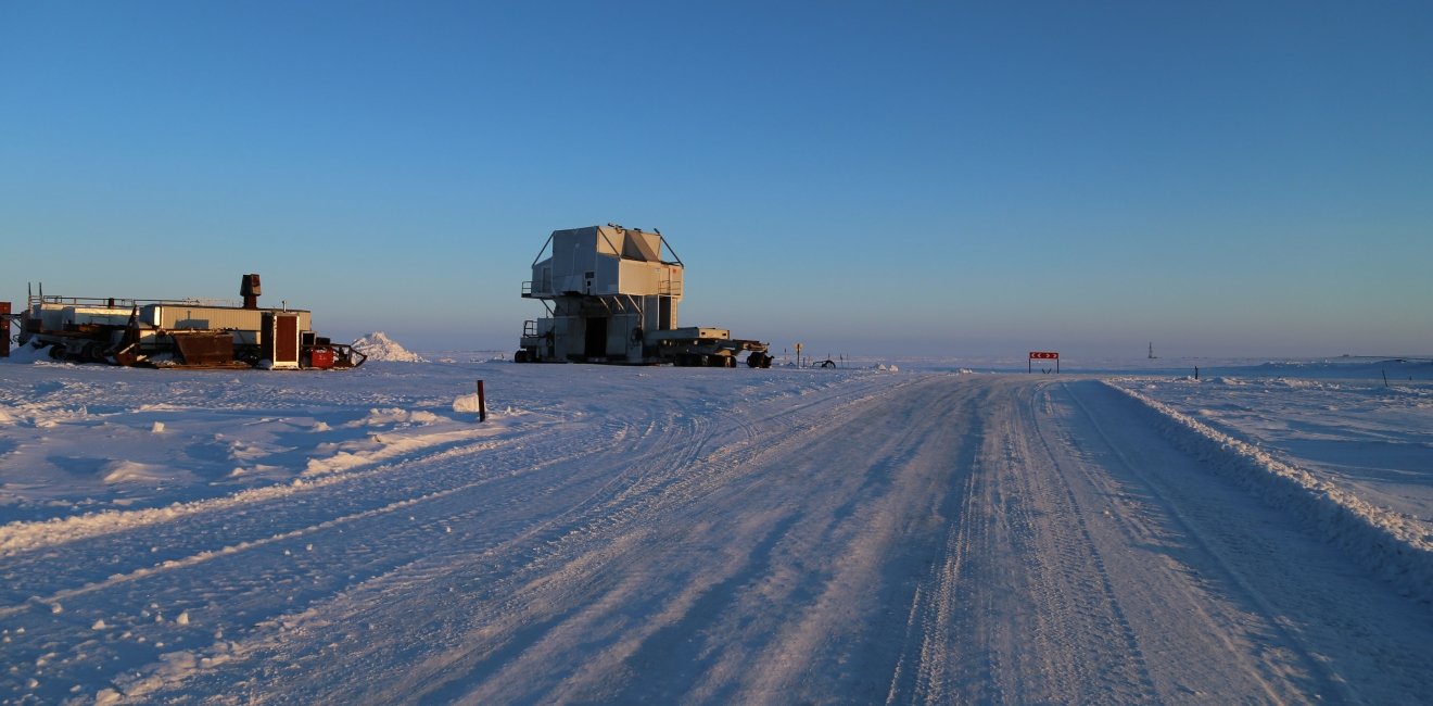 Snow road with a substructure of the oil work over rig and a distant view of the drilling rig at an oilfield in the tundra in winter. Source: Shutterstock