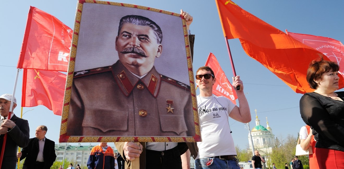 Orel, Russia - May 1, 2017: May demonstration. Young men with Stalin portrait and red Communist flags. Source: Alexey Borodin/Shutterstock