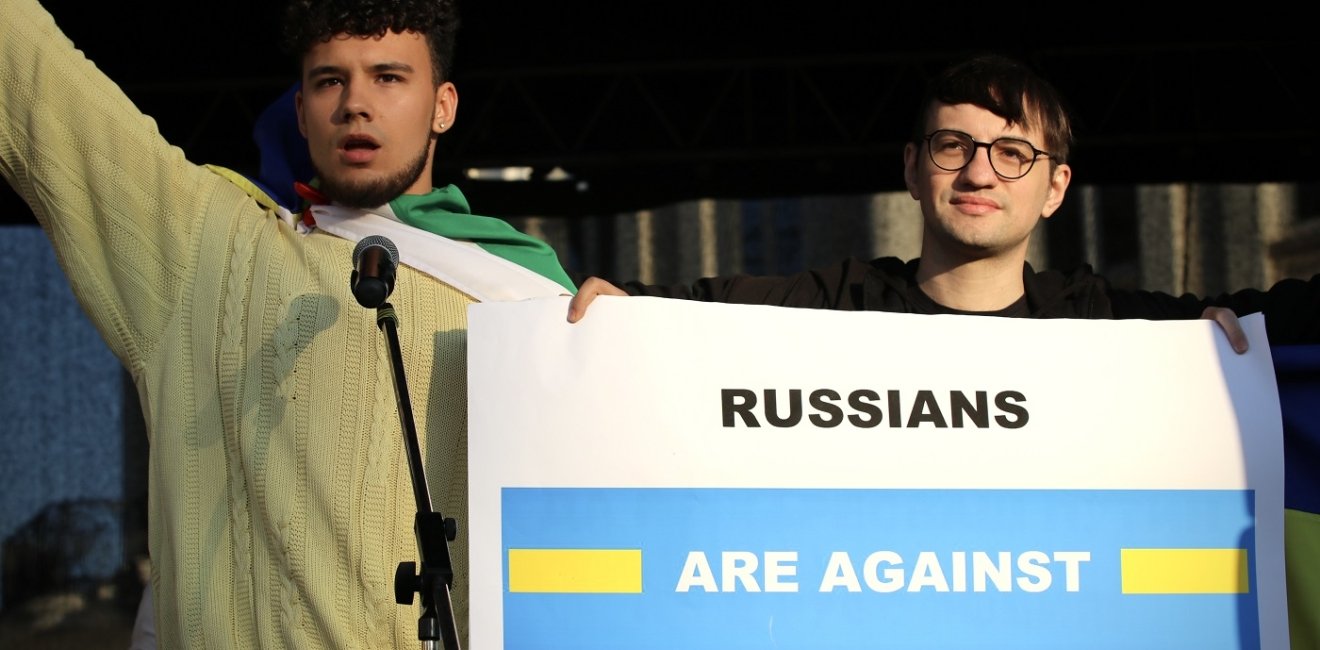 two protestors hold up a sign reading "Russians are against the war"