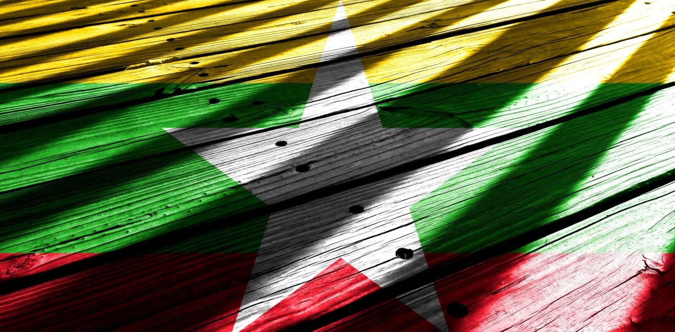 The flag of Myanmar with bars of light shining on it.