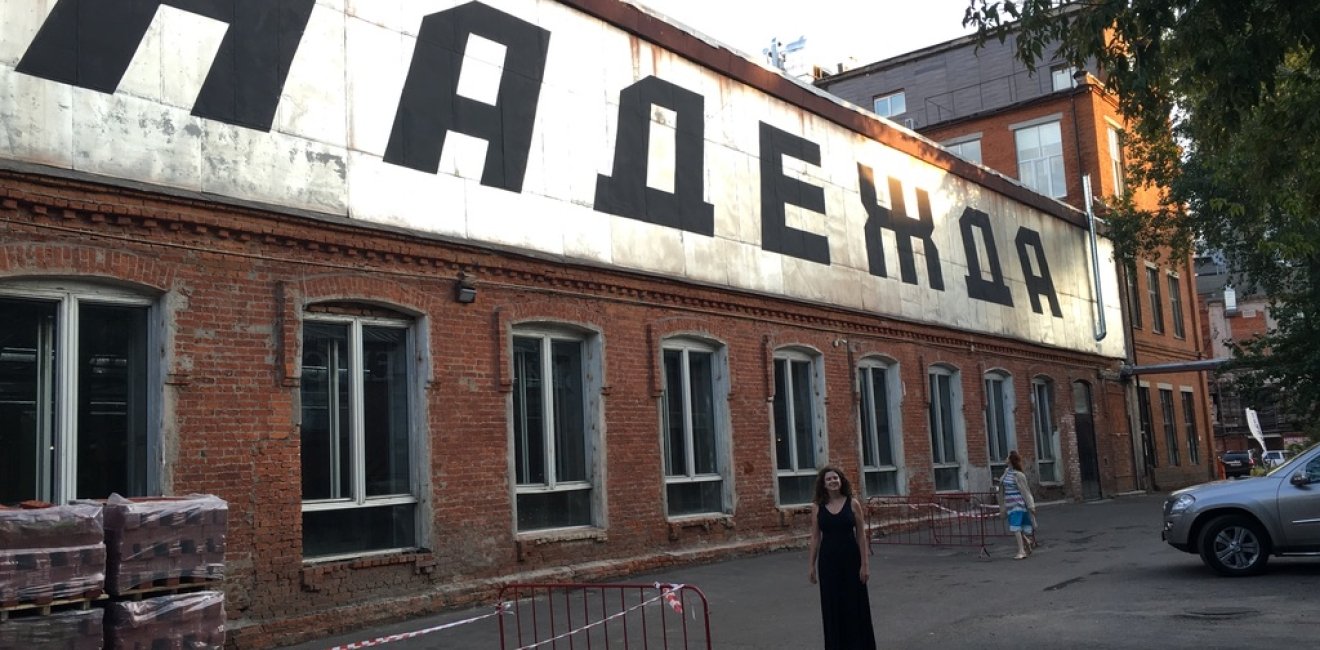 Kathryn David stands in front of a large sign that reads "hope" in Russian