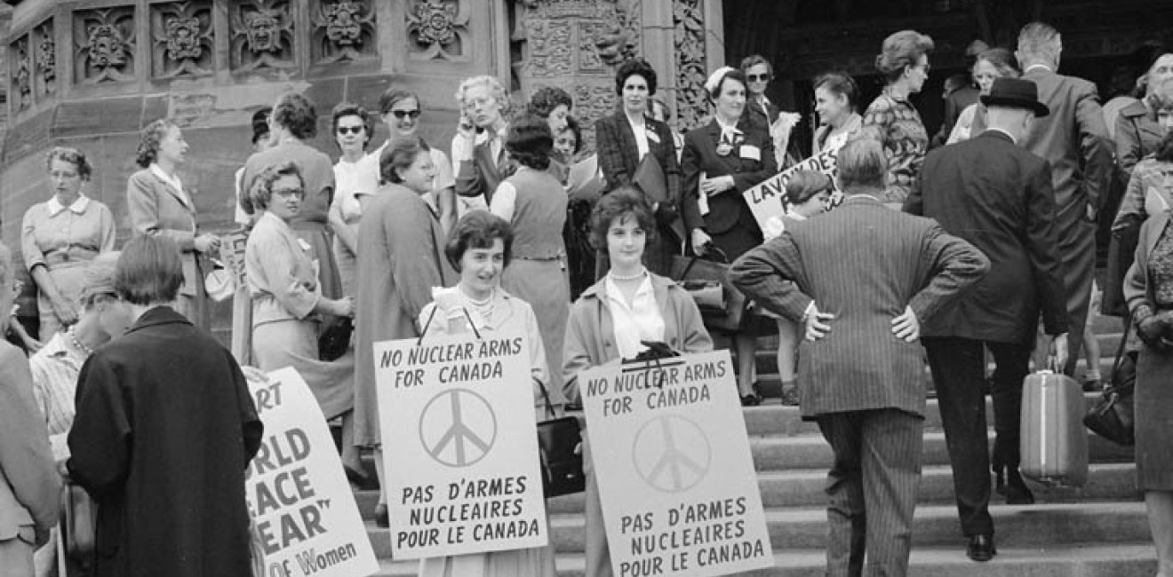 Women on steps holding signs "No Nuclear Arms for Canada