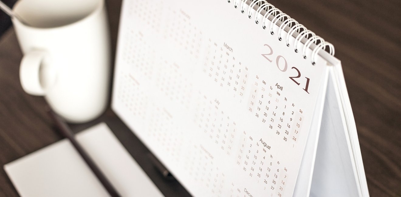 A coffee mug sits next to a desk calendar that shows the year 2021