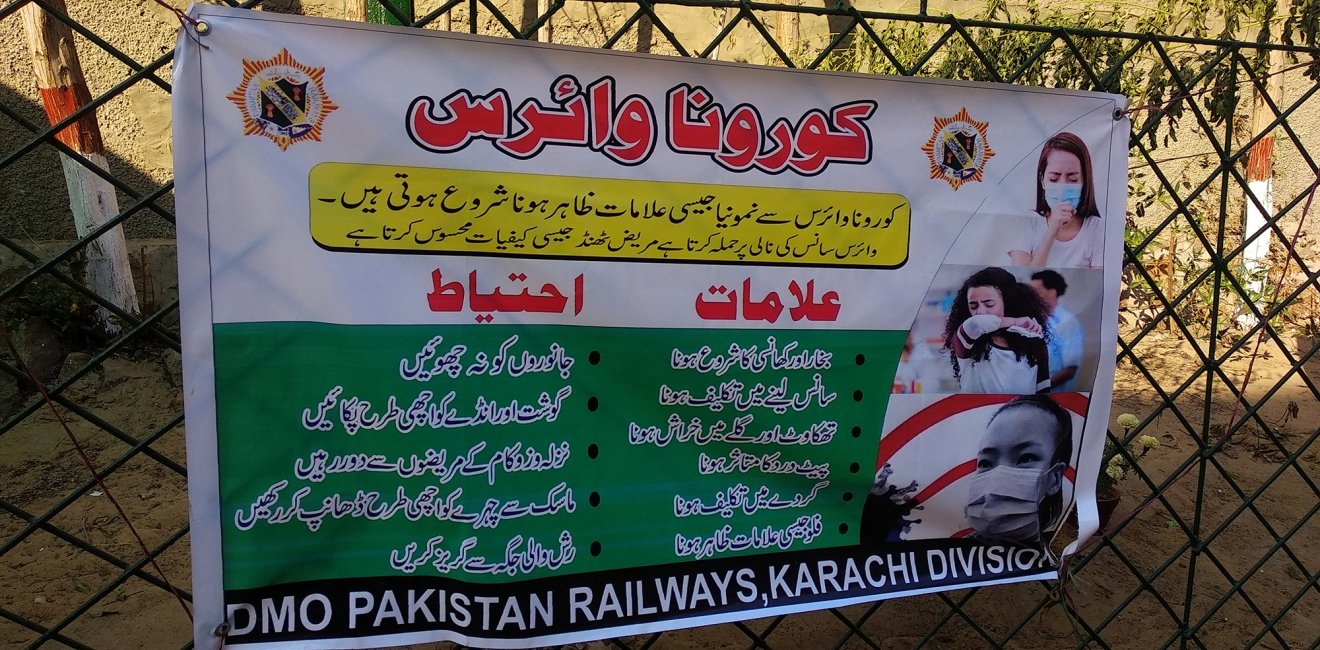 A banner in Urdu language describing the symptoms and precautions for Corona Virus at City railway Station - Karachi, Pakistan. 