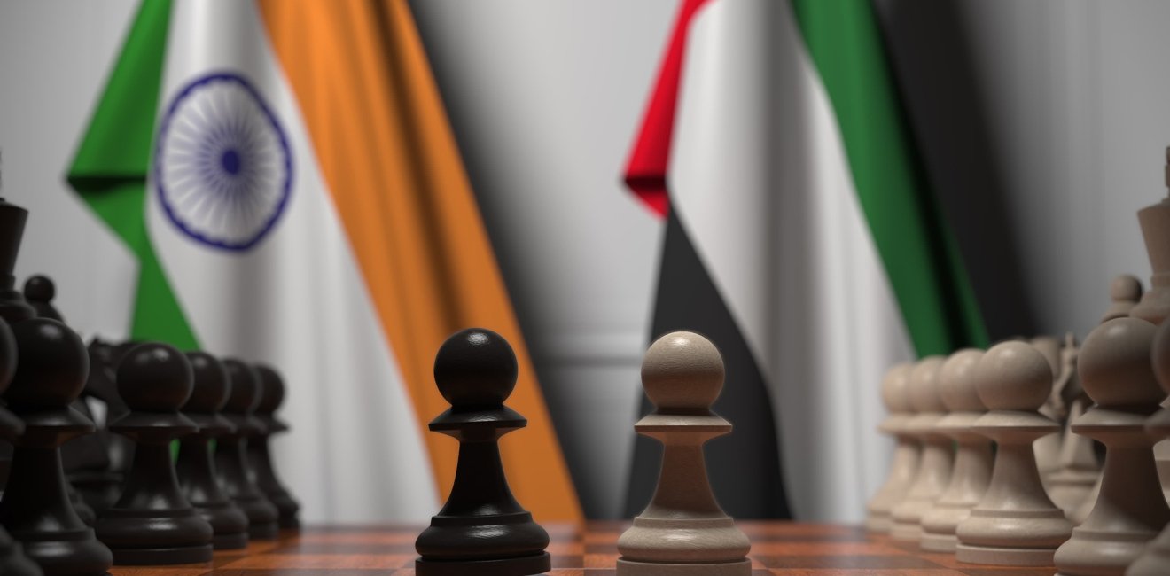 Flags of India and UAE behind pawns on the chessboard.