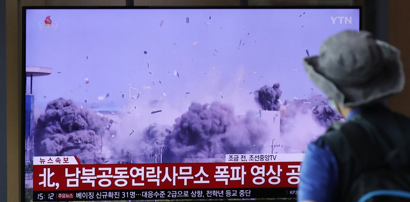 A man watching a TV screen showing a news program with a video of the demolition of the inter-Korean liaison office building in Kaesong, North Korea.