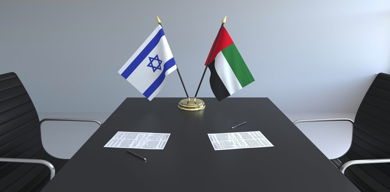 The flags of Israel and the UAE on a conference room table.