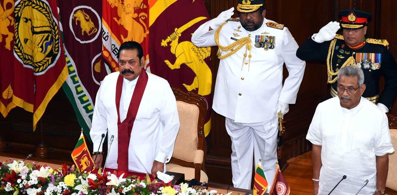 Prime Minister Mahinda Rajapaksa and President Gotabaya Rajapaksa stand in front of two soldiers at a swearing in ceremony