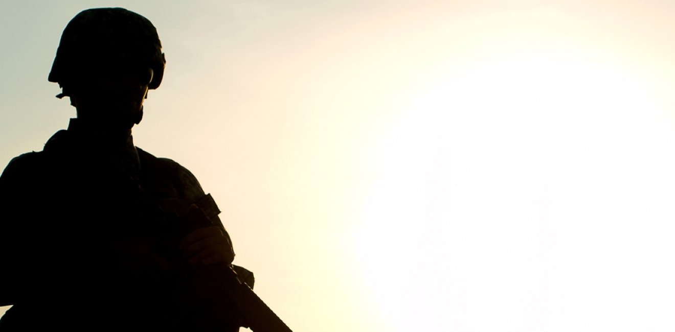 A soldier is silhouetted against a sunset