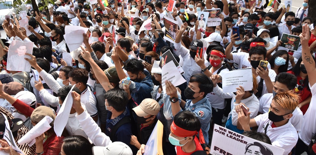 A group of people gather for a protest, many holding signs saying We Want Our Leader Free.