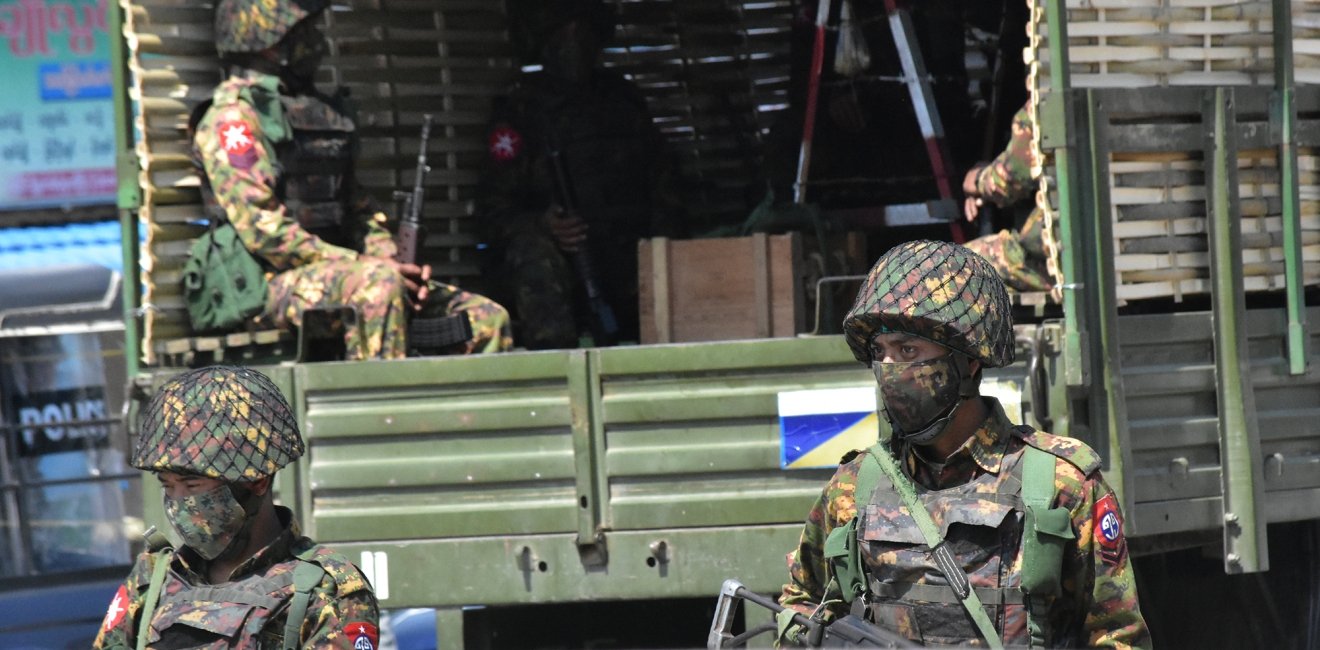 Soldiers stand behind a military vehicle in Myanmar.