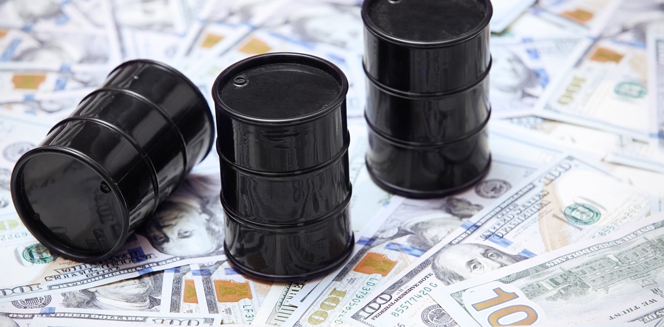 A picture of three oil barrels on a stack of U.S. currency