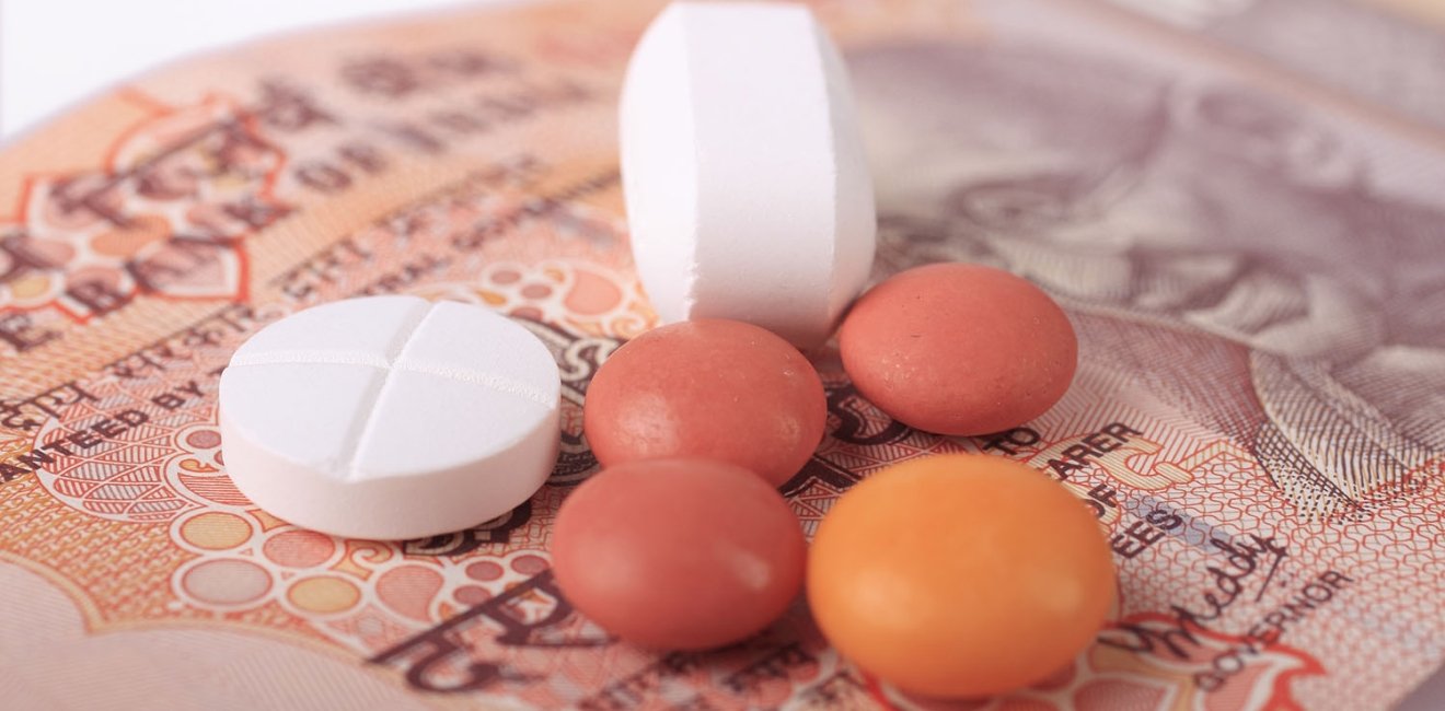 A group of different shaped pills sits on paper currency from India.