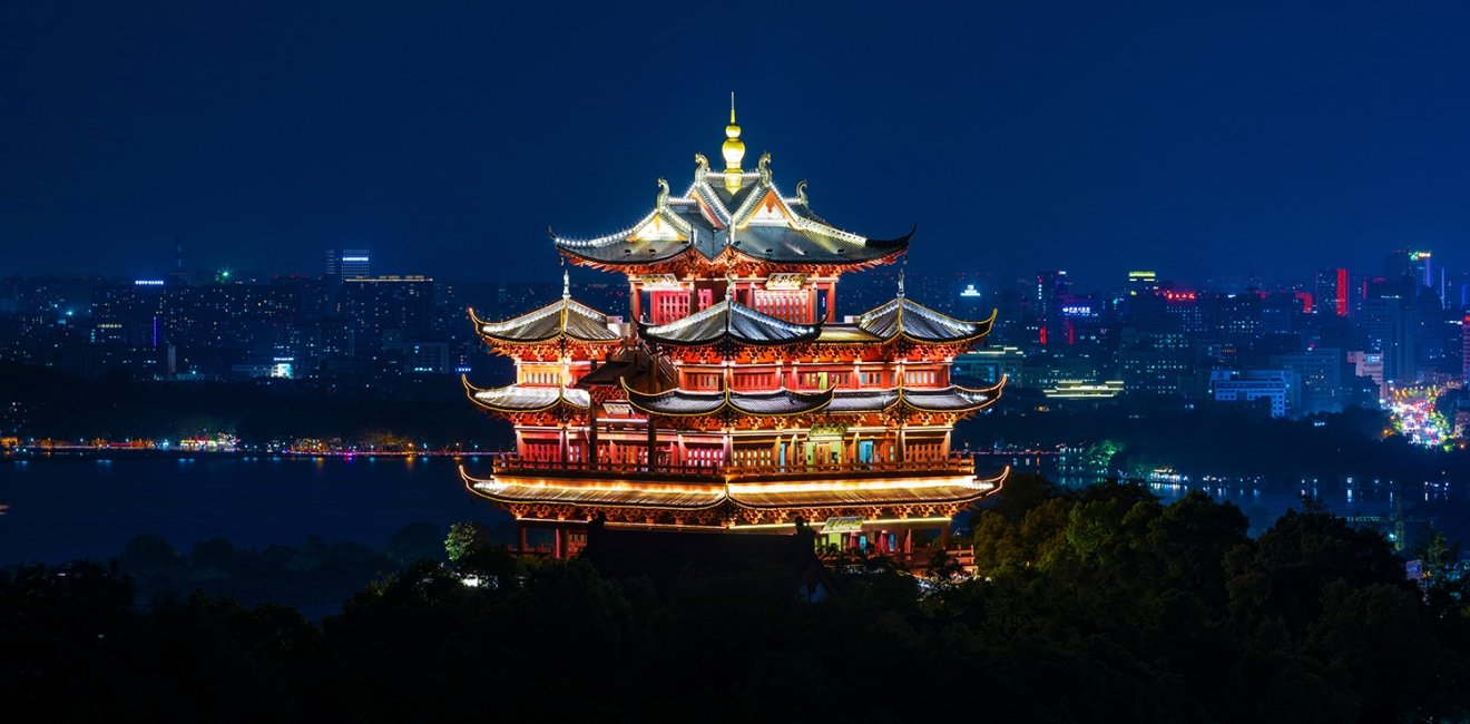 An ancient temple is lit up in front of a modern city skyline.