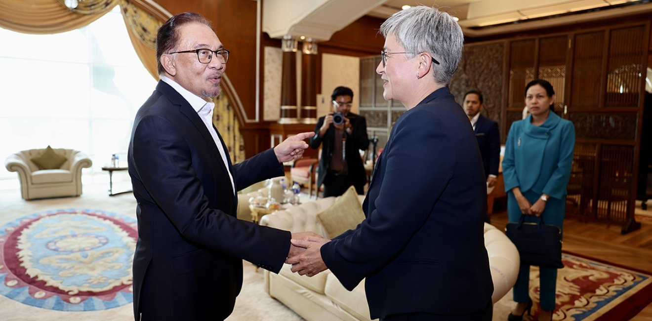 Anwar Ibrahim shakes hands with Penny Wong in an ornate office.