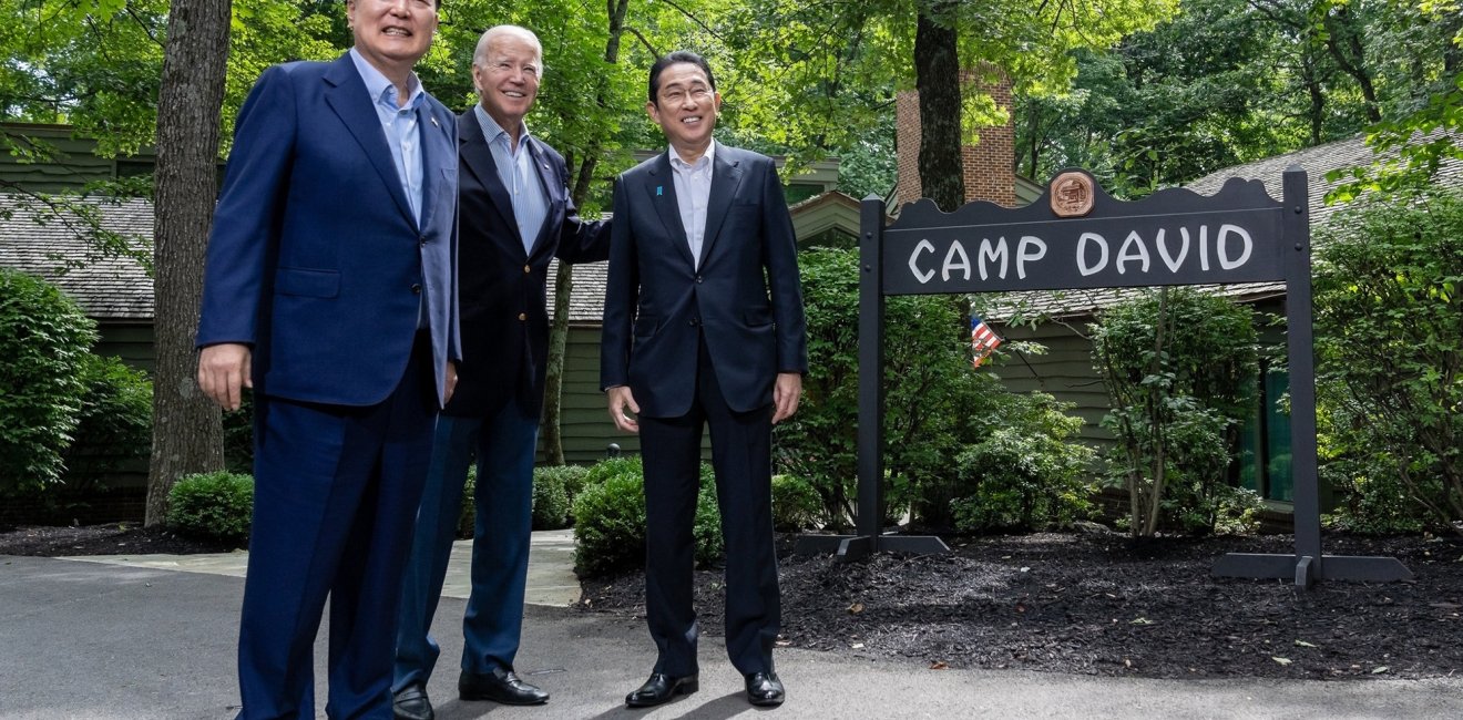 Presidents Yoon and Biden stand with Prime Minister Kishida in front of the sign for Camp David.