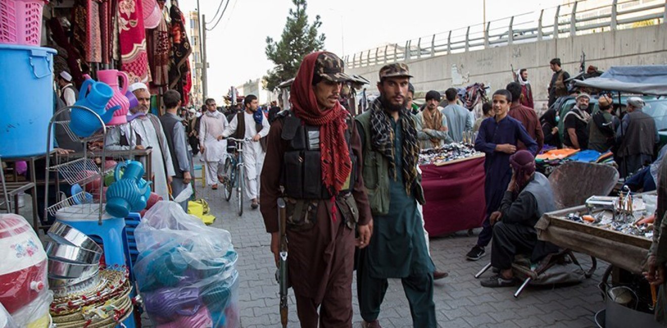 Two men who appear to be soldiers are walking through a crowded market.