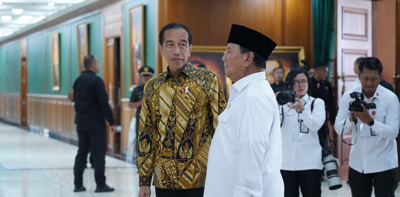 Two men are talking while photographers look on.