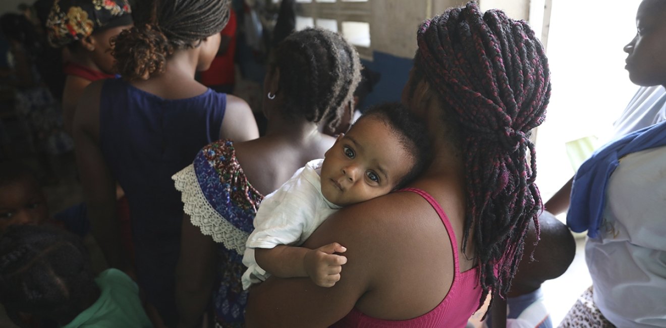 A woman waits for her baby's check-up at a school that serves as a shelter for people displaced by gang violence in Port-au-Prince, Haiti, Friday, Aug. 23, 2024. (AP Photo/Odelyn Joseph)