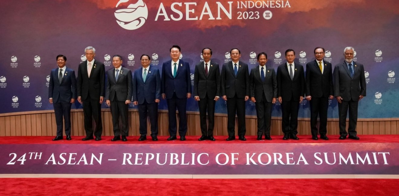 A group of ASEAN leaders stand in front of the logo for the 2023 ASEAN Summit.