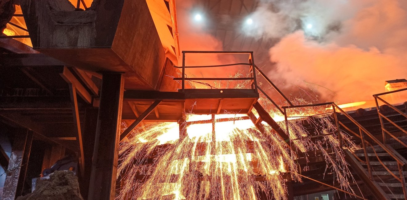 Sparks fly from a production smelter furnace.