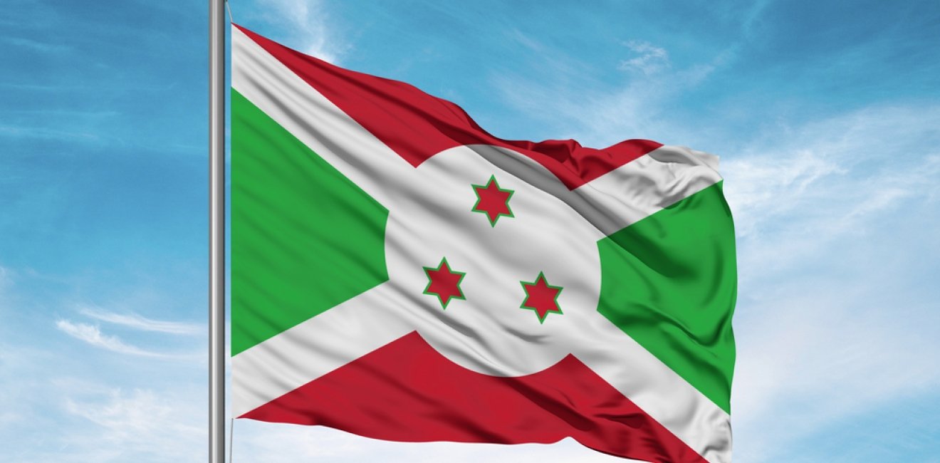 Burundi national flag cloth fabric waving on beautiful sky.