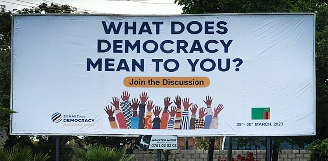 Billboard displaying "What does democracy mean to you"? for the 2023 Summit for Democracy