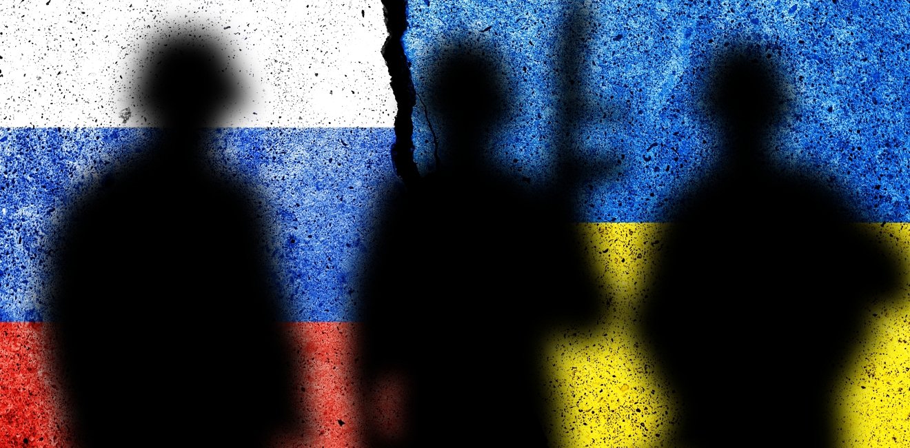 soldier silhouettes stand before Russian and Ukrainian flags