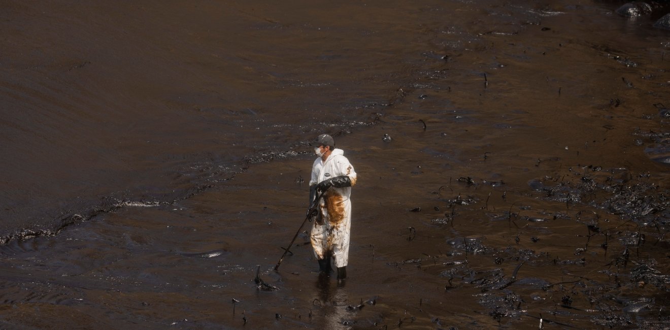 Callao, Peru; January 19, 2022: Workers clean after an oil spill, on Cavero Beach in the Ventanilla district of Callao. From La Pampilla Repsol refinery