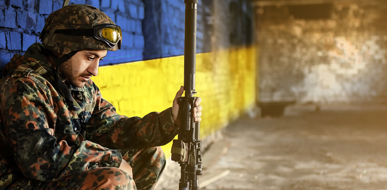 Soldier in front of Ukraine flag wall