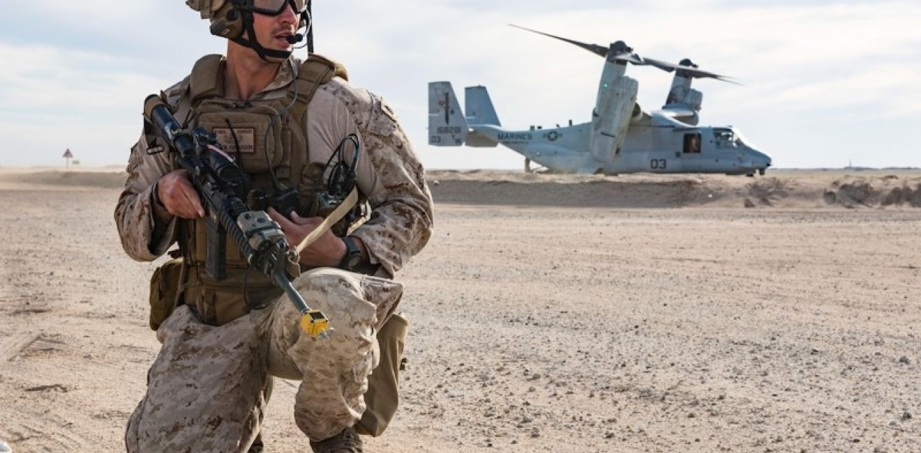 U.S. soldier crouches in front of aircraft