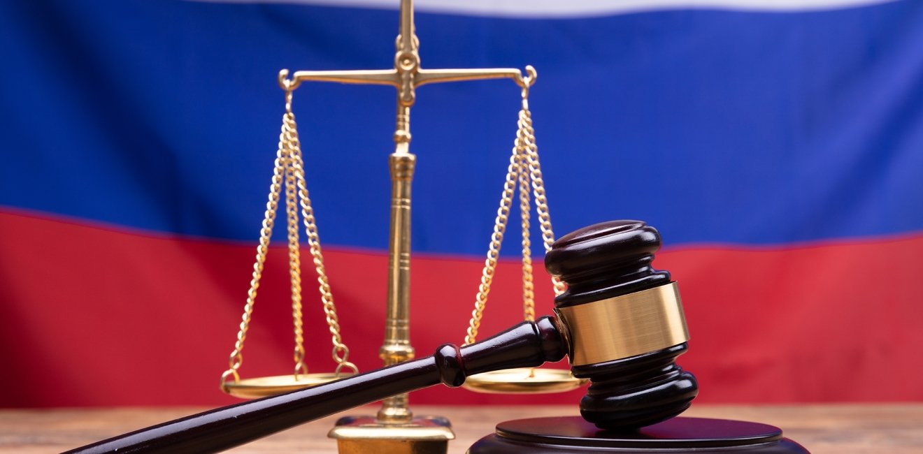 Judge Gavel And Justice Scale On Desk In Front Of Russian Flag