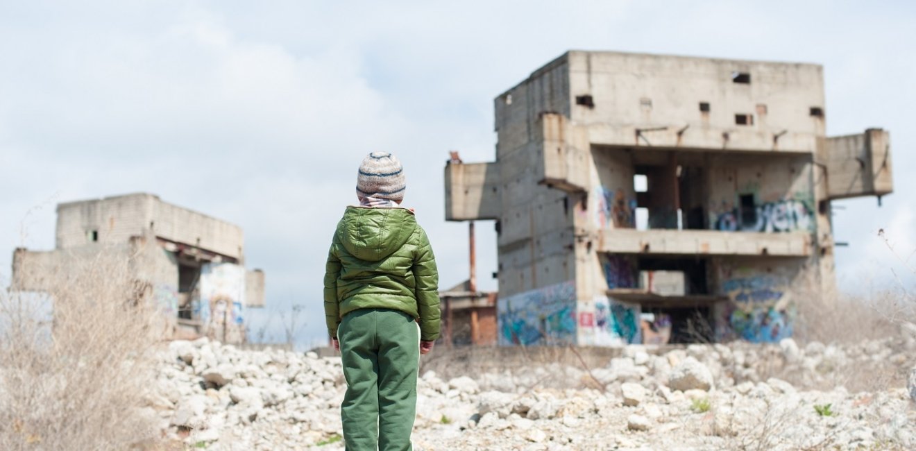 image of young boy looking over a bombed-out building 