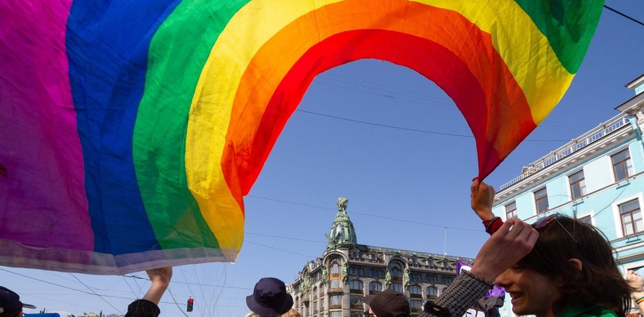 Person waving a pride flag on a busy street