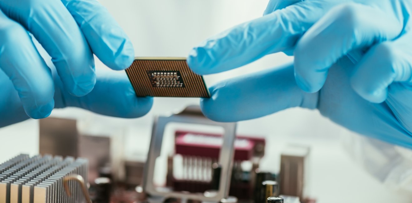 partial view of engineer holding microchip near computer motherboard