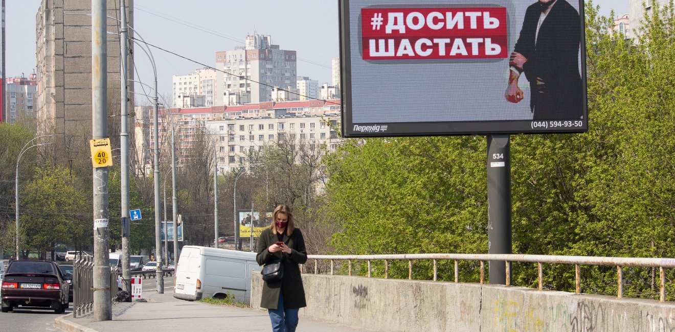 April 17 2020: Girl in a mask on a city street and a banner with the image of the mayor of Kyiv, sign reading "Do not go" in the Ukrainian language