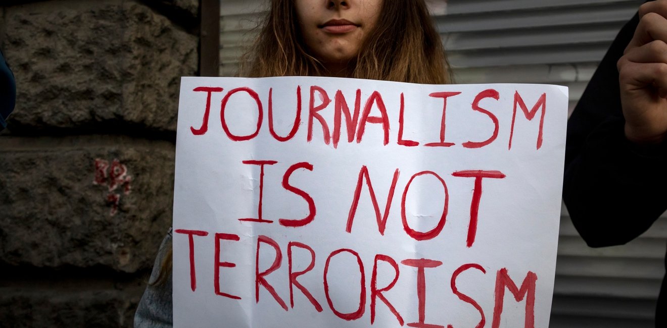  A woman holds a banner with the inscription "Journalism is not terrorism" in support of independent journalists