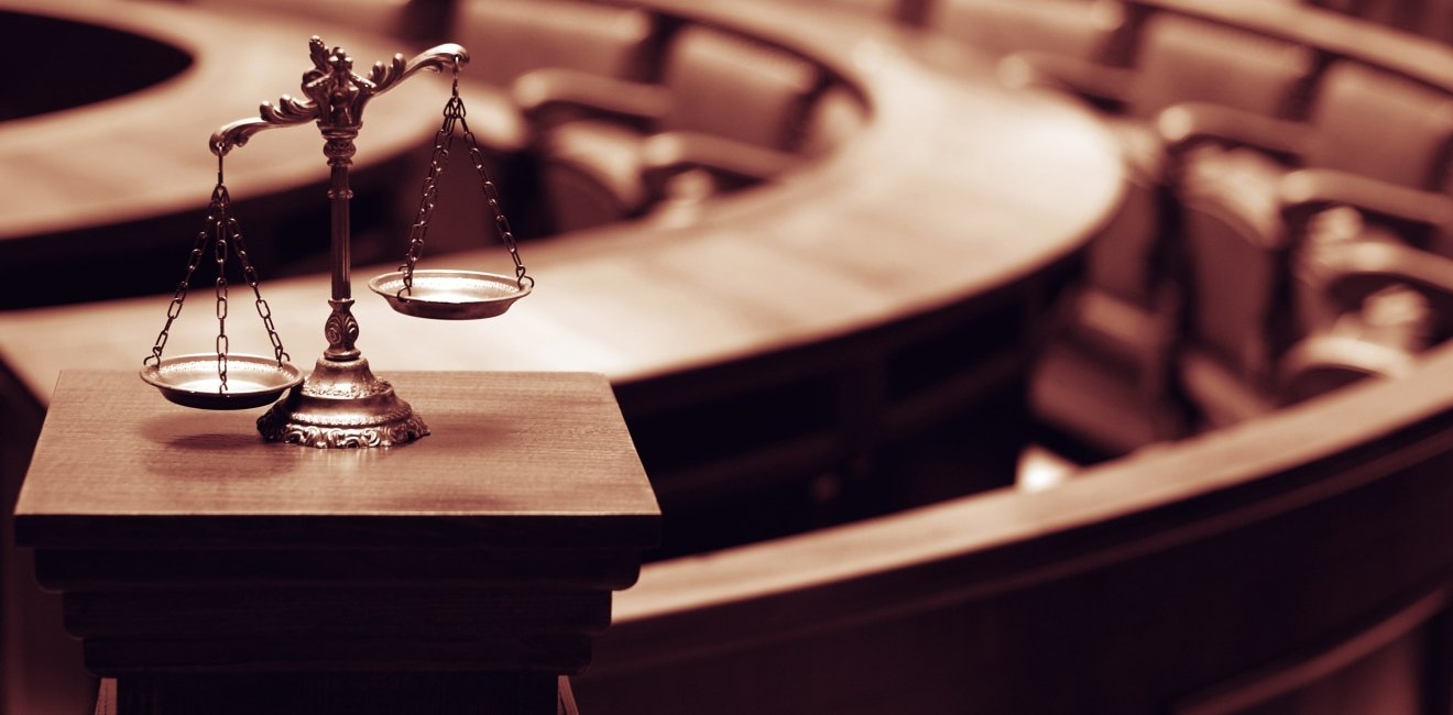 Image of a scale representing justice in front of a court room