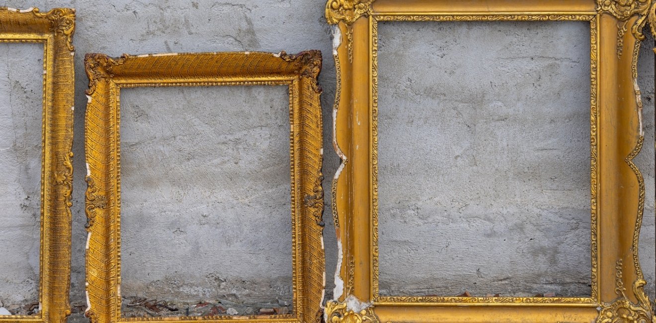 Three golden frames leaning against a wall