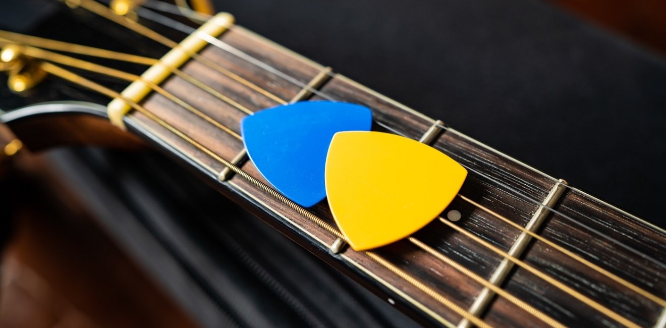 Blue and yellow guitar picks on an acoustic guitar