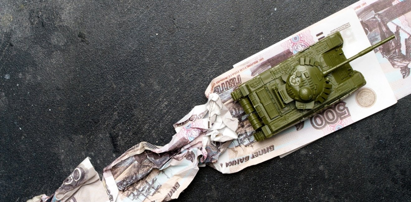 Economic crisis in Russia concept. Toy military tank on Russian rubles. War conflict in Ukraine, economic sanctions and inflation in Russia