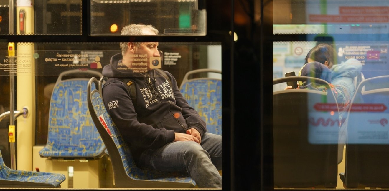 Image of a man on a bus through the bus's window 