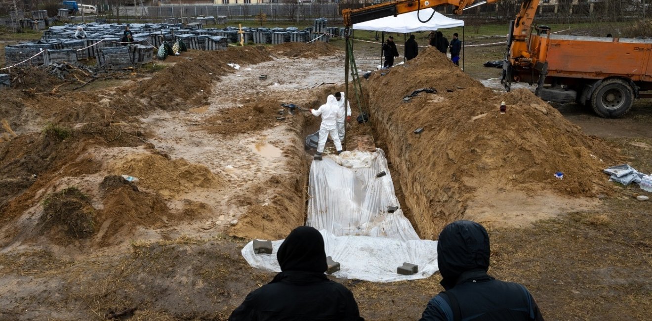 Forensic experts are working to dig up bodies from a clandestine grave found behind a church in the town of Bucha.