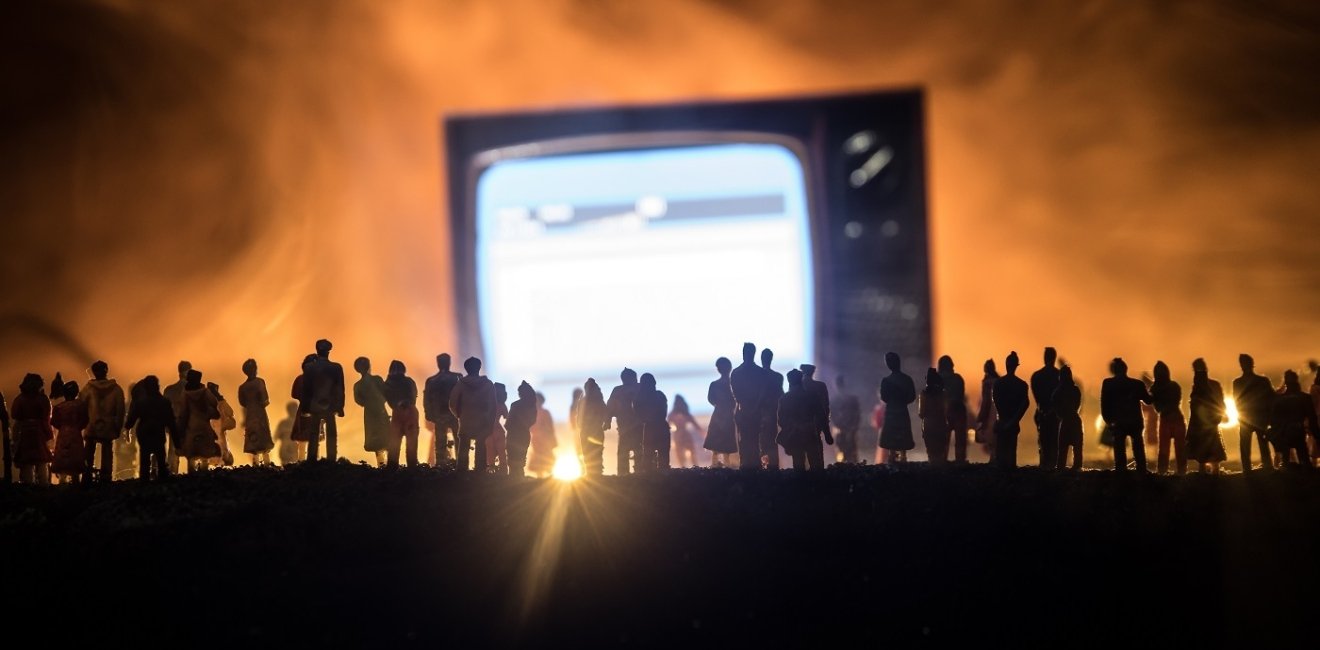 Gathering of people surrounding a large screen